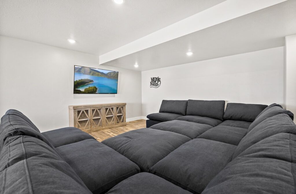 Home theatre room with big screen TV and a large sectional couch.