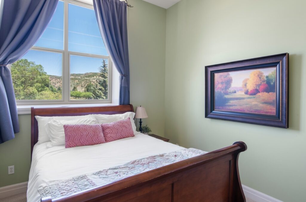 Cozy bedroom with green painted walls, and overlooking the Bear Lake hills through the bedroom window.